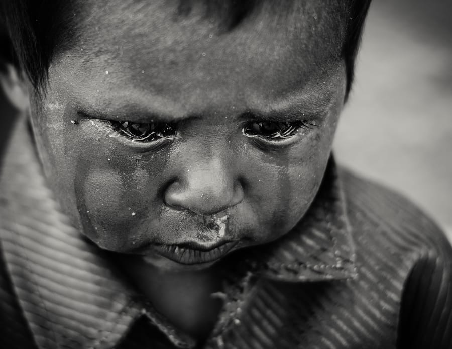 A Small Storm. A little boy crying a river on the street — one of the children forced into begging, undone by hunger. Aspur.