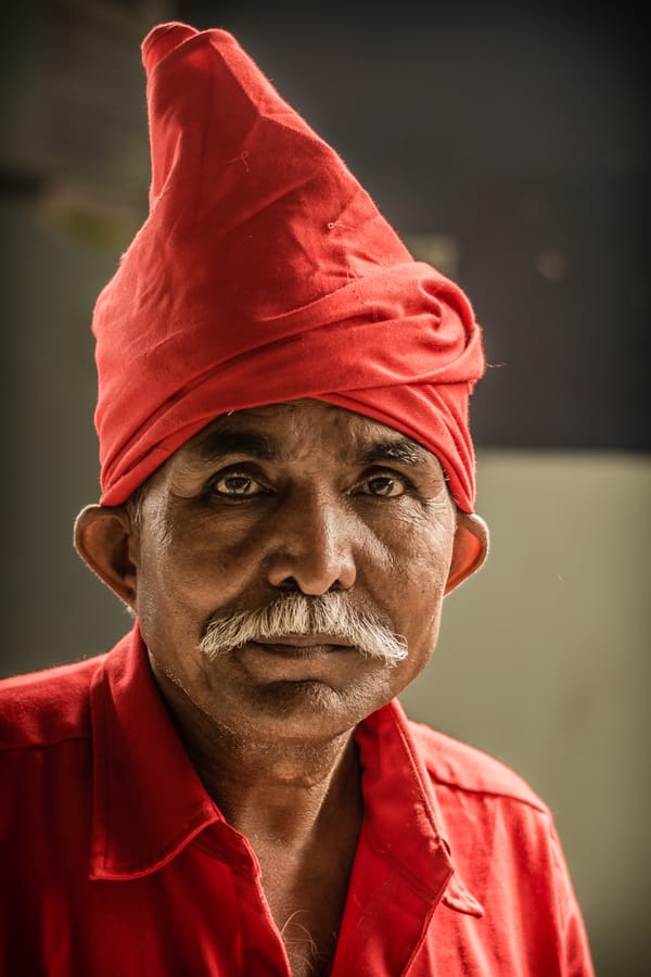 An Indian Coolie. A coolie — a porter who carries passengers' luggage at India's railway stations, known anywhere by his red turban and uniform. Gopalapuram.